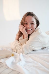 uśmiechnięta kobieta leży na łóżku w piżamie